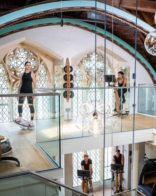 Featured image of people working out on raised fitness area featuring original stained glass windows
