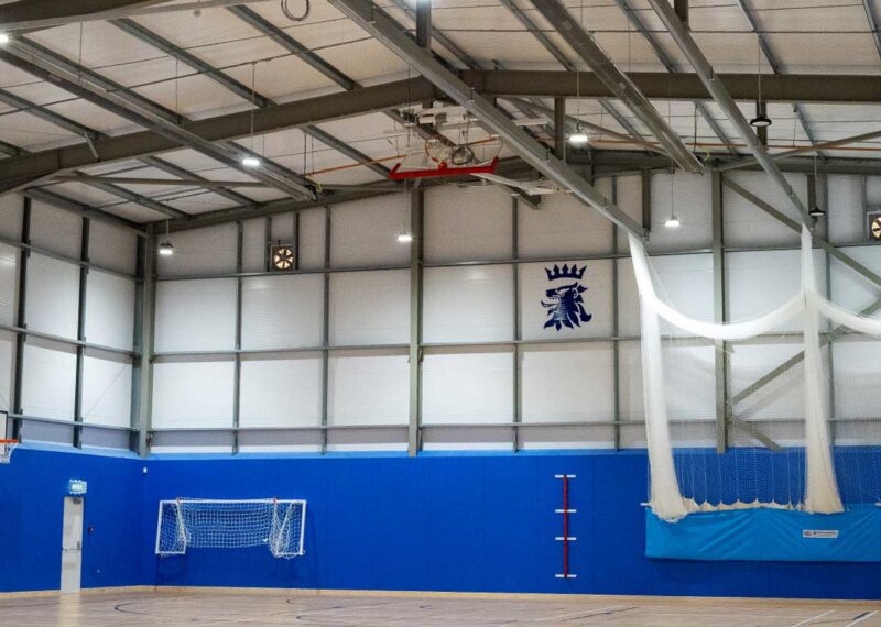 Interior of completed steel frame sports hall featuring school crest.