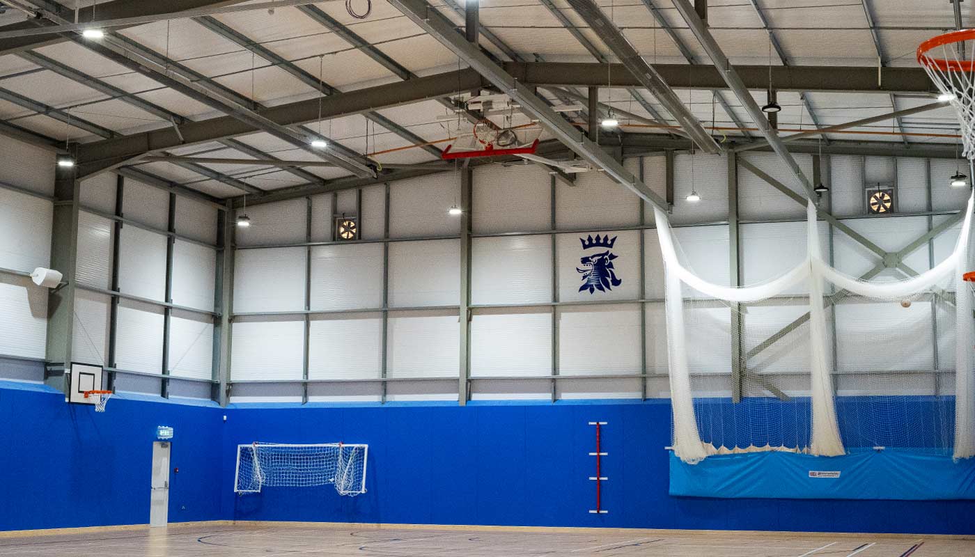 Interior of completed steel frame sports hall featuring school crest.