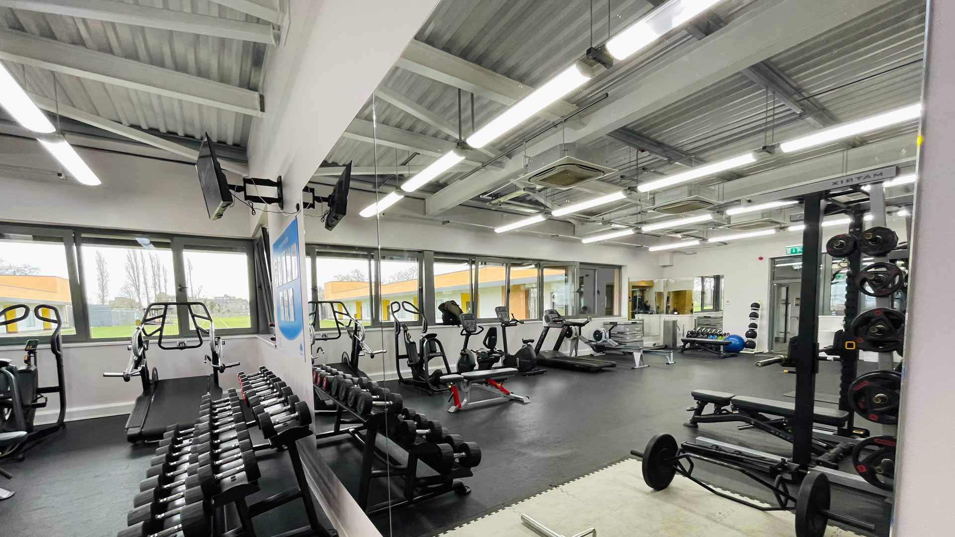 Inside the Barn Elms Sports Centre gym building. Steel frame building with gym equipment.