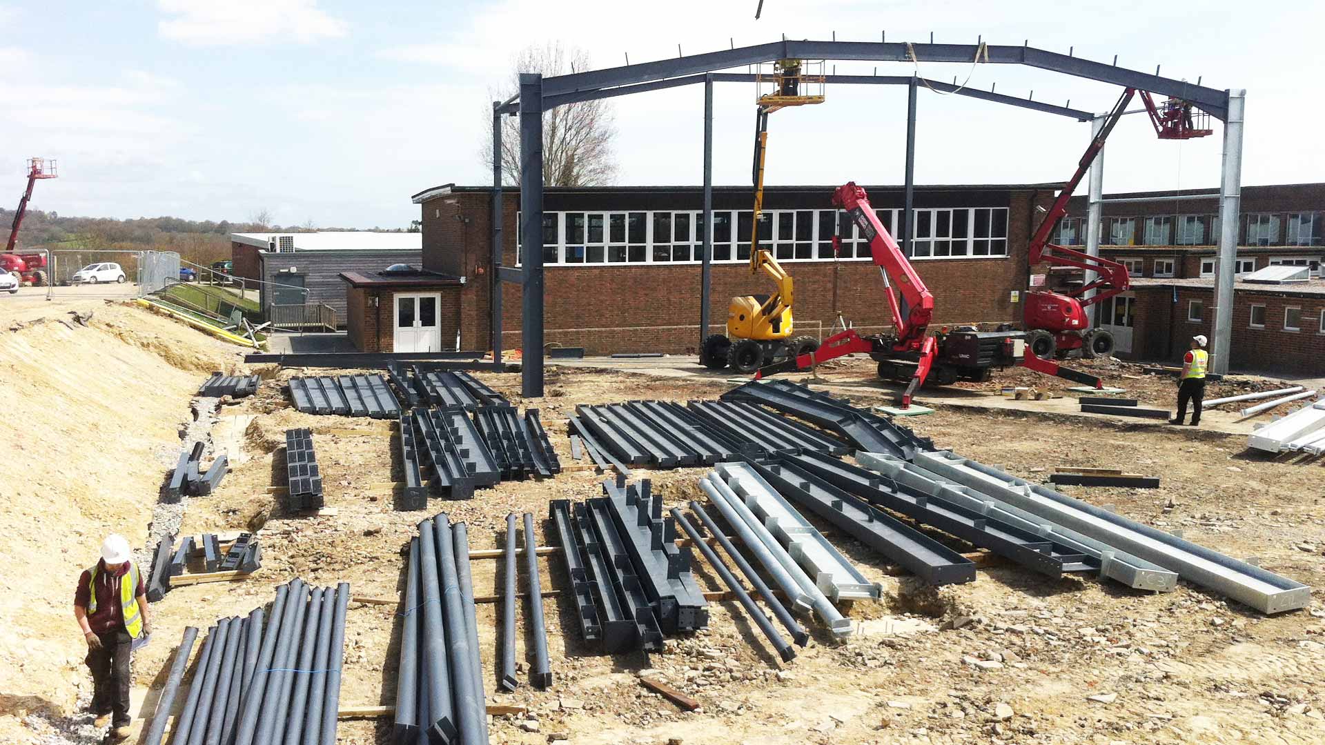 Steel frame sports hall under construction. Steel frame components lying on the floor.